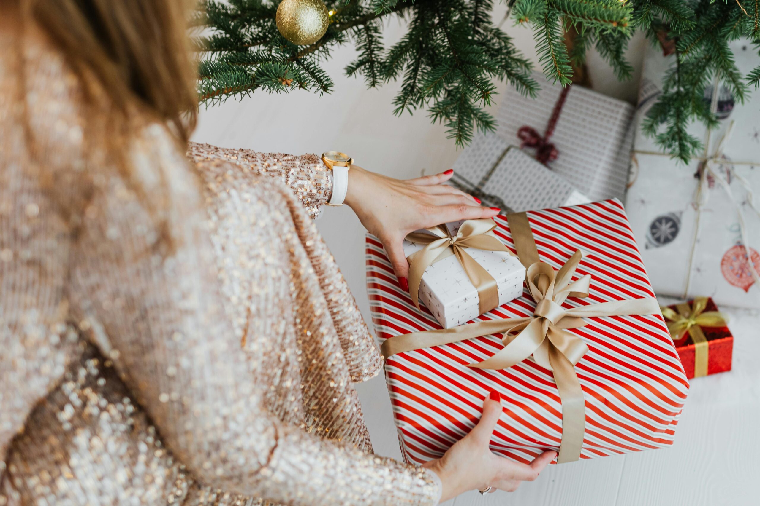 mujer-agachada-colocando-bajo-el-arbol-dos-regalos-de-navidad