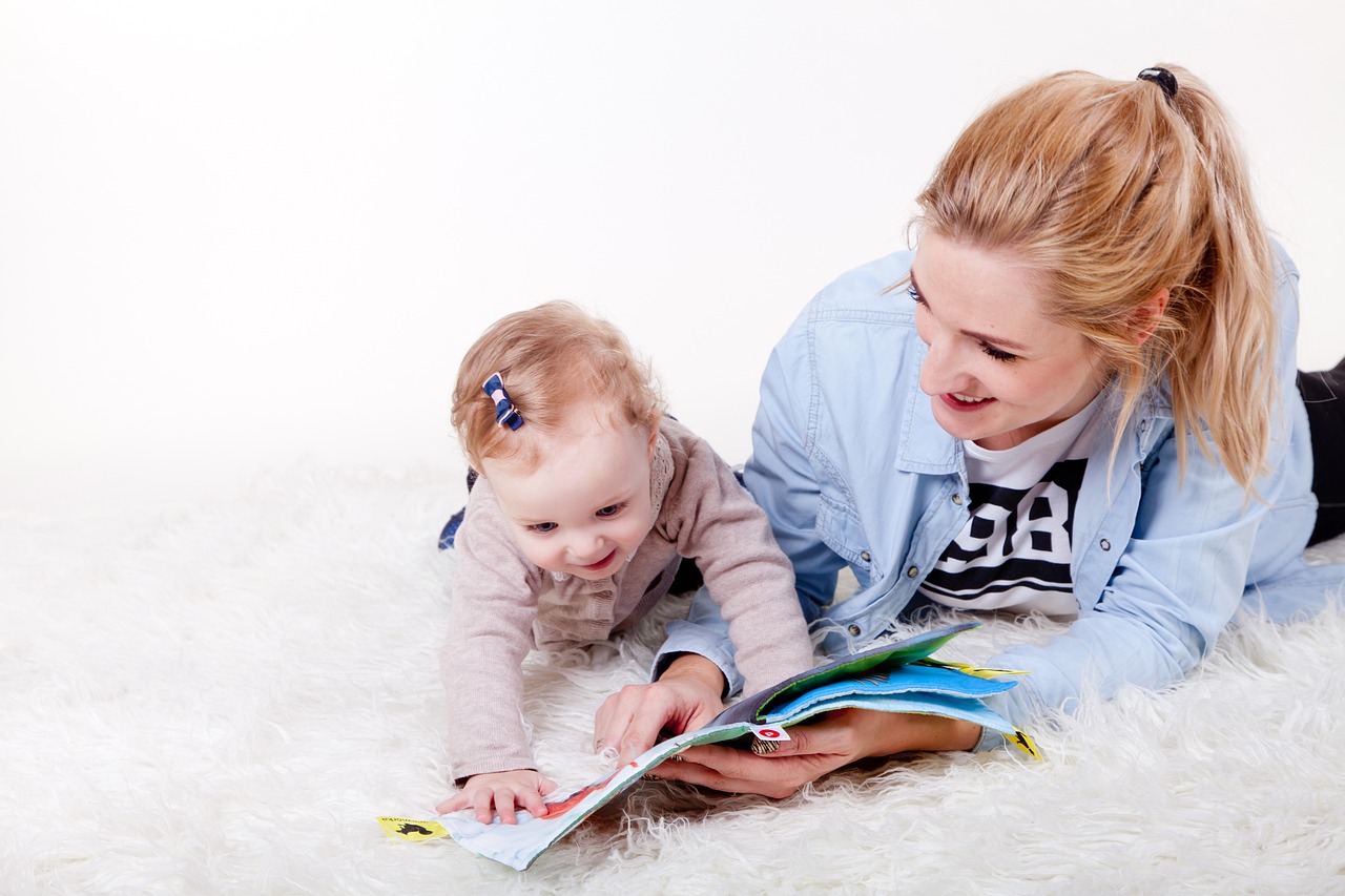 madre-con-su-bebe-tumbadas-en-una-alfombra-leyendo-un-cuento-infantil-uno-de-los-mejores-planes-en-familia-que-puede-hacer-una-madre-con-su-hija